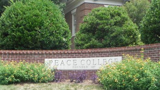 sign of "peace college" outside of the school on a brick wall