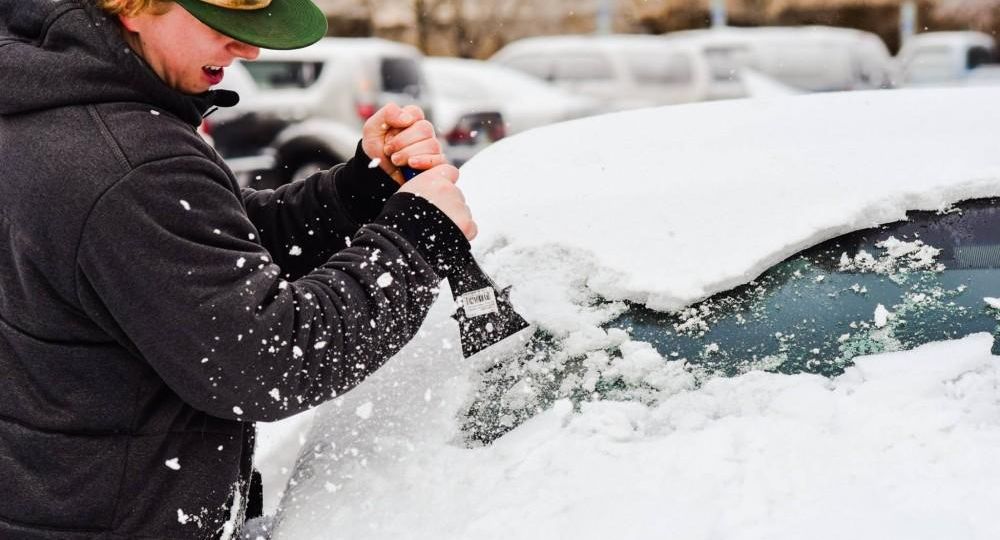 Christian Neal struggles to scrape ice and snow off of a vehicle