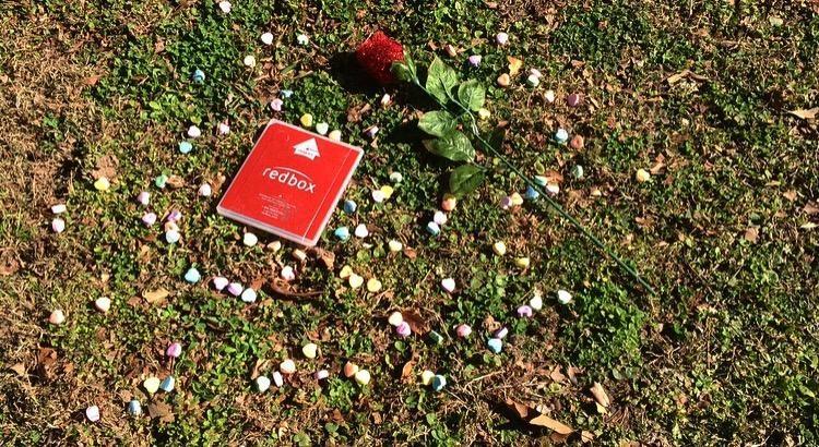 Valentines card, candy, and rose on the ground